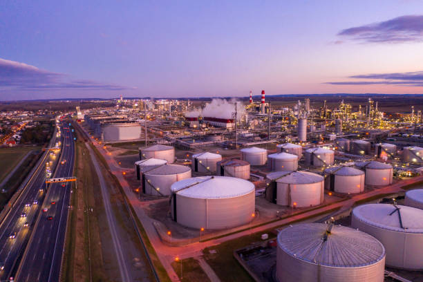drone point of view shot of an oil refinery under a moody sky at sunset.
